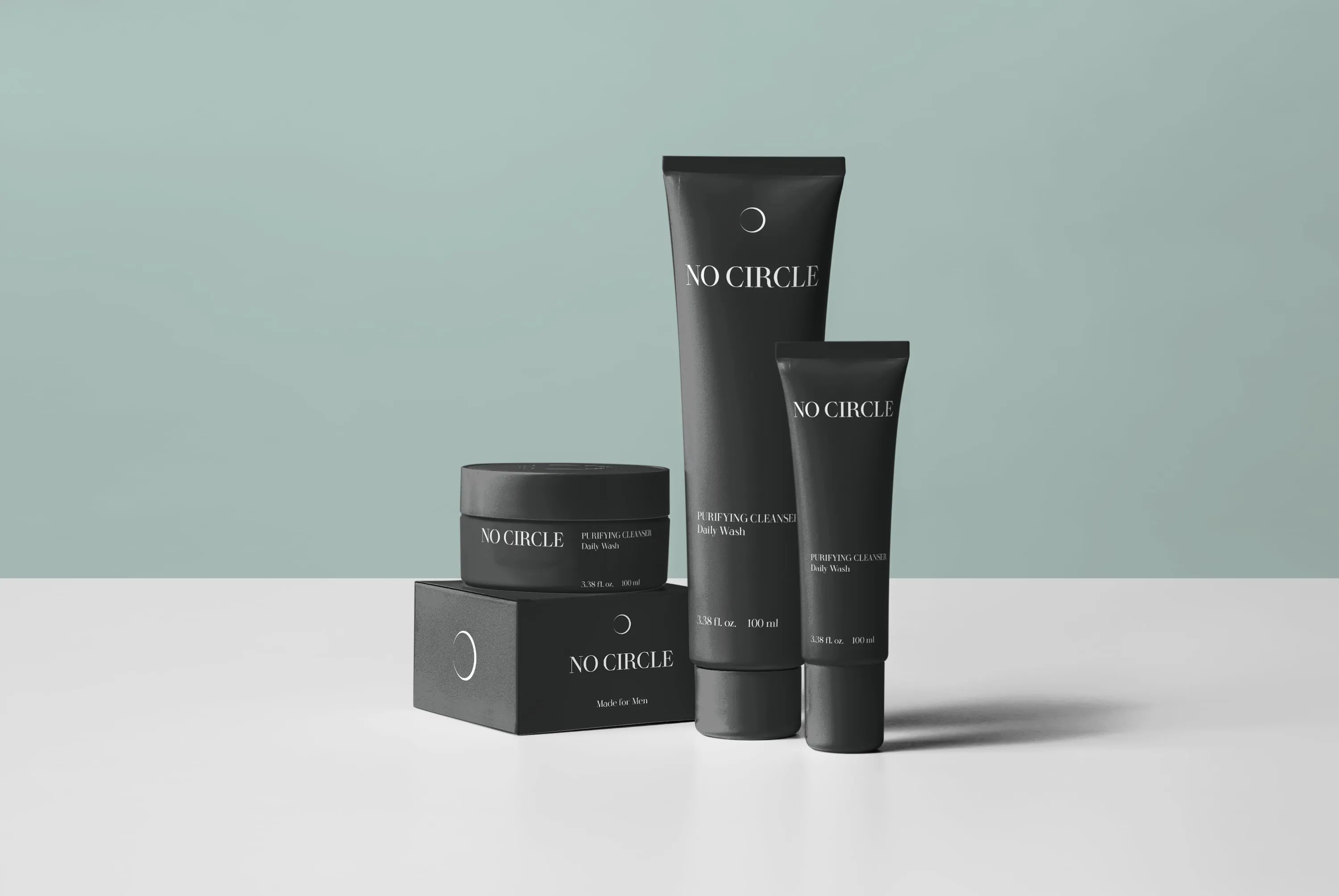 No Circle skincare — matte-black tubes and jar with minimal white branding on sage-green studio background