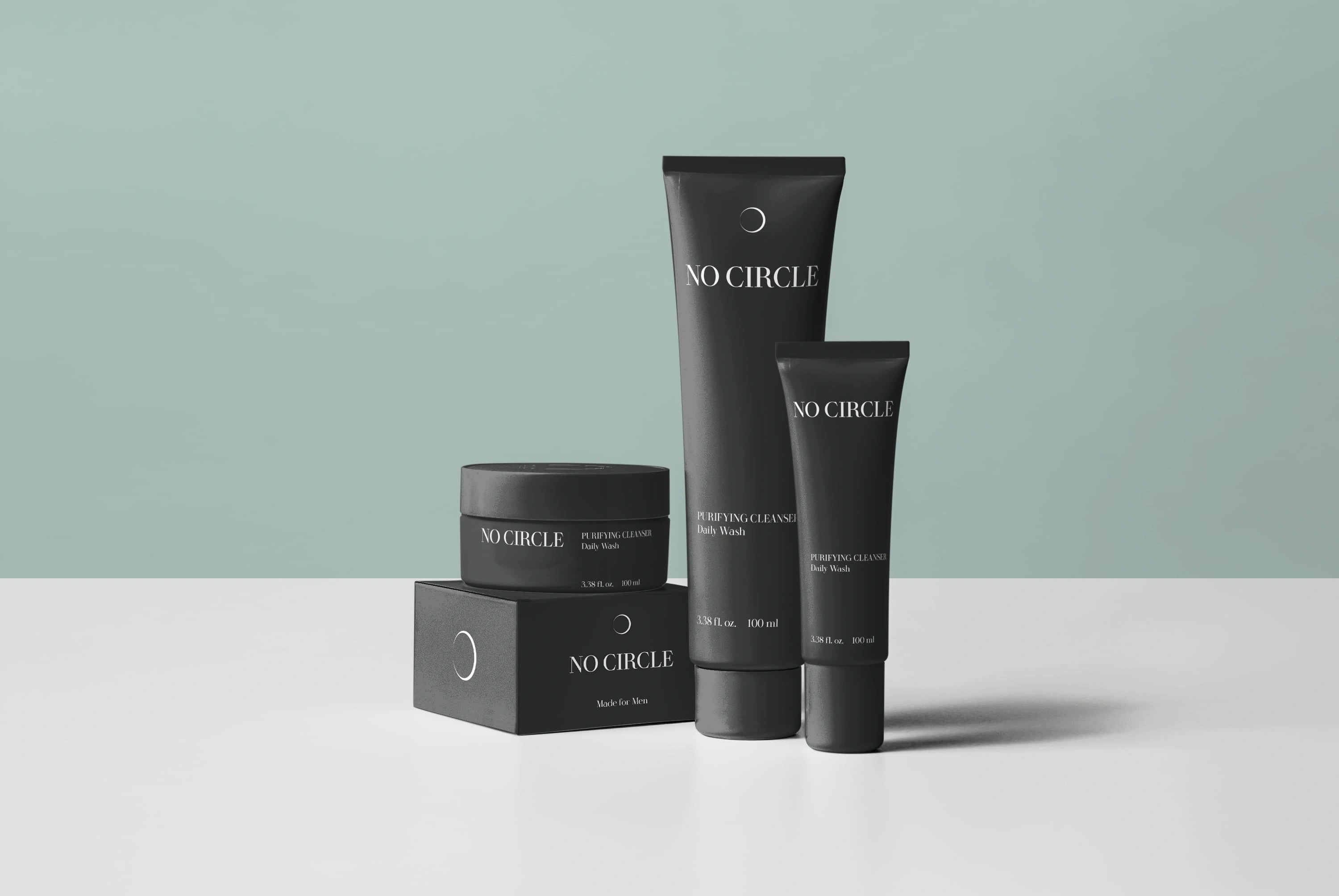 No Circle skincare — matte-black tubes and jar with minimal white branding on sage-green studio background